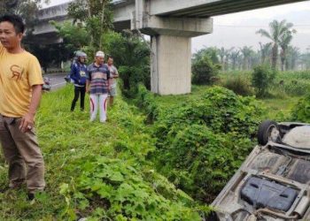 Warga melihat mobil Honda Jazz yang terperosok ke parit di jalan Bandara Kualanamu Desa Penara Kebun Kecamatan Tanjung Morawa Kabupaten Deliserdang Selasa, (24/5/2022). TRIBUN MEDAN/INDRA GUNAWAN