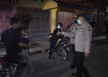 Petugas tampak membagikan masker kepada pengendara kendaraan bermotor.