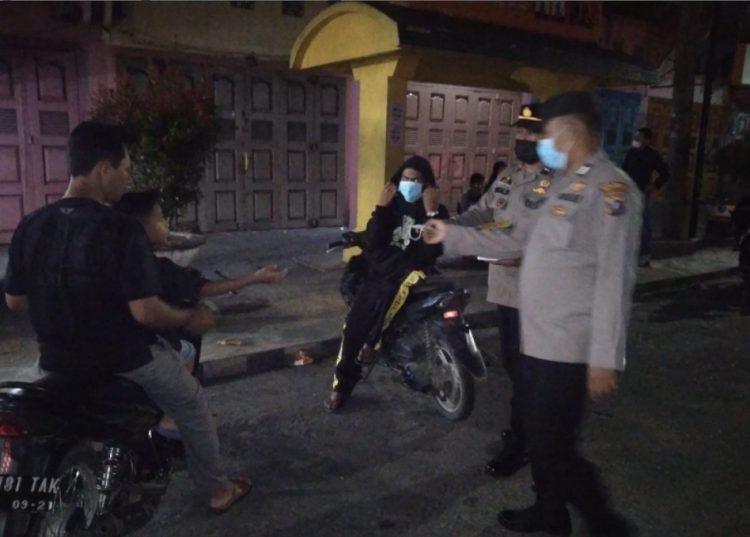 Petugas tampak membagikan masker kepada pengendara kendaraan bermotor.