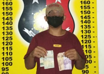 Foto pelaku pungli saat memegang barang bukti uang.