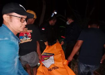 Petugas kepolisian saat mengevakuasi mayat korban dari lokasi kejadian.
