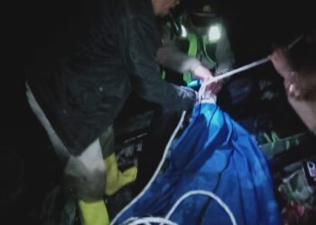 Petugas kepolisian saat mengevakuasi jenazah korban dari lokasi kejadian.