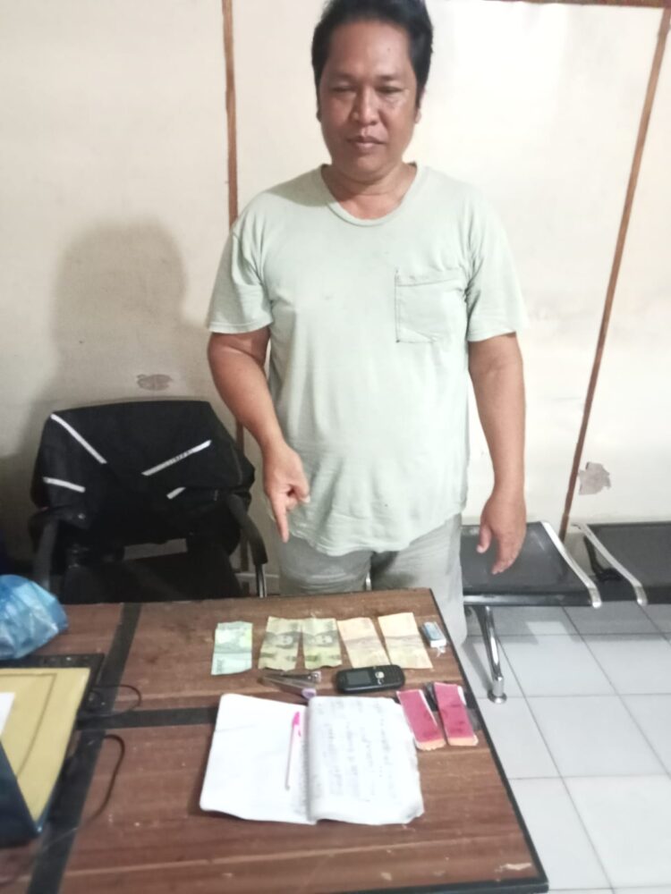 Foto terduga pelaku judi tebak angka saat menunjuk barang bukti.