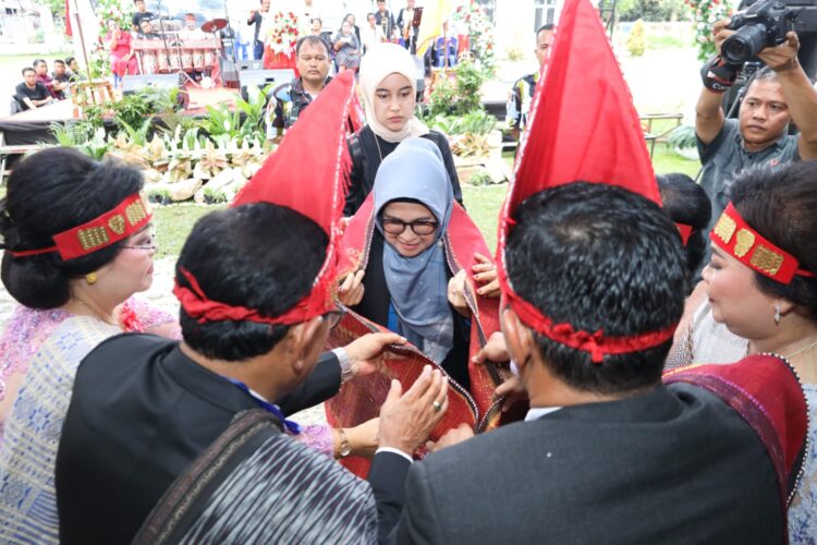 dr Susanti saat terima ulos dari PPSD Siahaan, di Jalan Gereja, tepatnya di Lapangan SMP YP HKBP, Minggu (12/03/2023).