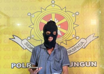 Foto pelaku judi Togel saat memegang barang bukti.