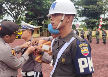 Kapolres Simalungun, AKBP Ronald F.C Sipayung, menyematkan pita kepada salah seorang personel sebagai tanda dimulainya Ops Patuh Toba 2023, di Lapangan Apel Mako Polres Simalungun, Jalan Jhon Horailam, Pematang Raya, Kabupaten Simalungun, Senin (10/7/2022).