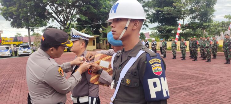 Kapolres Simalungun, AKBP Ronald F.C Sipayung, menyematkan pita kepada salah seorang personel sebagai tanda dimulainya Ops Patuh Toba 2023, di Lapangan Apel Mako Polres Simalungun, Jalan Jhon Horailam, Pematang Raya, Kabupaten Simalungun, Senin (10/7/2022).