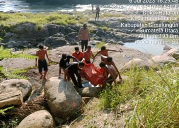 Polsekta Tanah Jawa dibantu warga mengevakuasi mayat dengan menggunakan kantong mayat.
