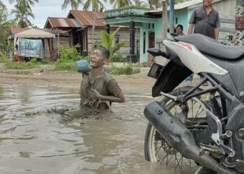 Warga melakukan aksi mandi lumpur dan mencuci sepeda motor di kubangan jalan rusak di Asahan. (Istimewa)