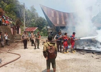 Kapolsek Lumban Julu AKP Robinson Sembiring bersama anggota berjibaku padamkan api pada kebakaran rumah di Lumban Julu, Senin (7/8/2023). IST