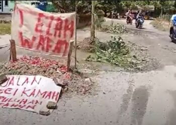 Warga Desa Sei Kamah, Kabupaten Asahan membuat kuburan di tengah jalan sebagai bentuk protes jalan rusak. (Foto: iNews/Ulil Amri)