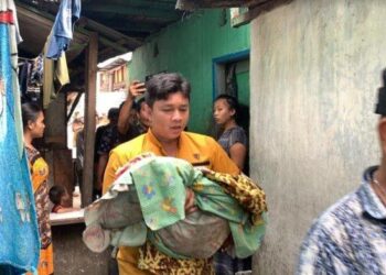 Seorang warga menggendong bayi berusia satu bulan yang tewas di dalam rumahnya di Jalan Mahkamah, Kelurahan Masjid, Kecamatan Medan Maimun, untuk dibawa ke mobil ambulans, Senin (2/10/2023). TRIBUN-MEDAN/ALFIANSYAH