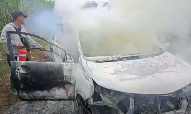 Petugas memadamkan api yang membakar mobil Toyota Avanza di tengah kebun tebu Kabupaten Langkat, Selasa (17/10/2023). (Foto: iNews)