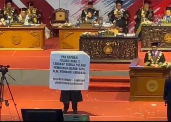 Wisudawan di Universitas Negeri Malang membentangkan spanduk minta tolong Kapolri viral di media sosial. (foto: istimewa)