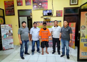 Foto pelaku pencurian saat diapit petugas kepolisian.