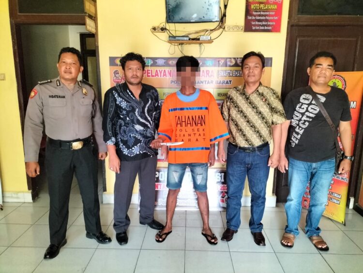 Foto pelaku saat diapit petugas kepolisian.