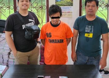 Foto tersangka diapit petugas kepolisian.