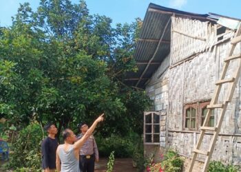 Warga memperlihatkan rumahnya yang rusak dihantam angin kencang.