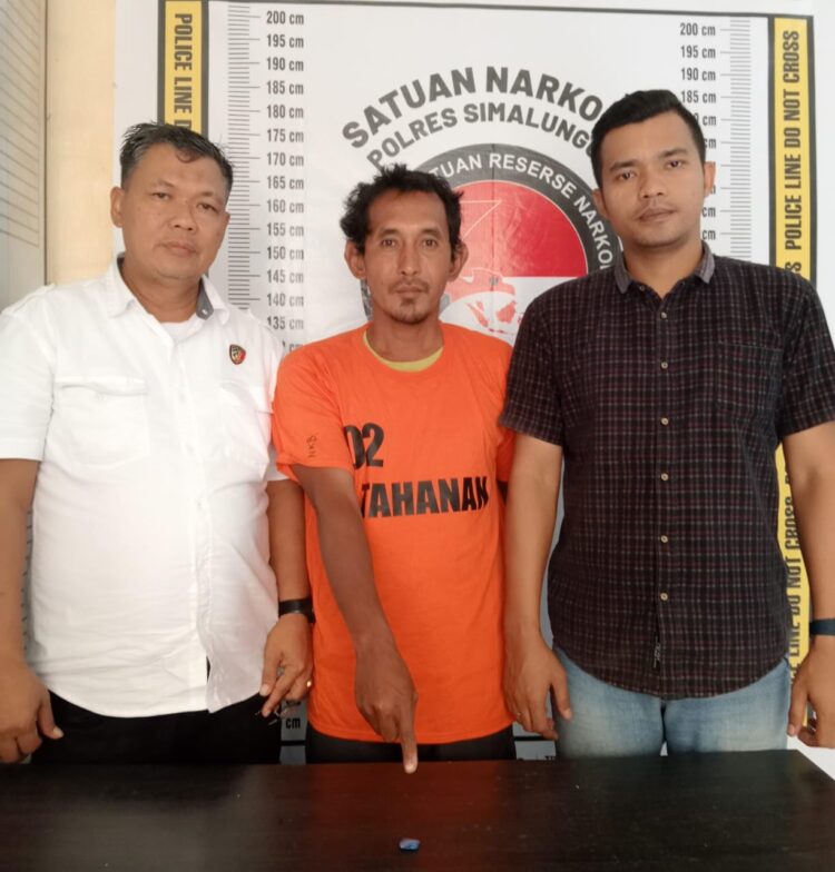 Foto pelaku diapit petugas kepolisian.