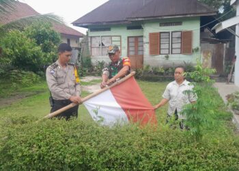 Bhabinkamtibmas Kelurahan Toba, Aipda Eko Silalahi, SH, bersama Babinsa, Serka J. Situmorang, kompak memasangkan bendera merah putih, di depan rumah warga binaannya.