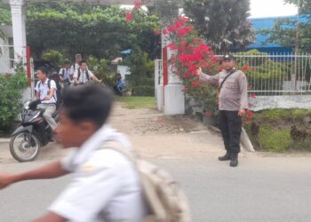 Personel Polsek Raya melaksanakan penjagaan dan pengaturan lalu lintas serta razia, di depan SMA Negeri 1 Raya Kahean, Jalan Panglima Nunut, Nagori Bangun Raya, Kecamatan Raya Kahean, Kabupaten Simalungun, pada Selasa (08/10/2024), pukul 13.00 WIB.