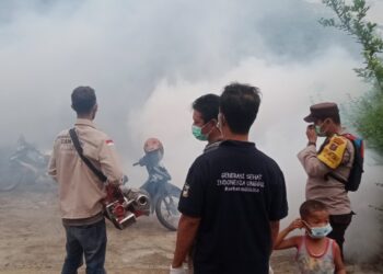 Polsek Sianțar Barat melalui Bhabinkamtibmas Kelurahan Teladan, Bripka Irwan Surya Darma, mendampingi Dinas Kesehatan (Dinkes) Kota Pematangsiantar melakukan pengasapan atau fogging.