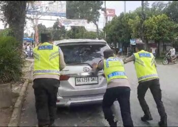 Tim Penggal Jalan Medan, simpang Terminal Tanjung Pinggir, menunjukkan kepeduliannya dengan mendorong mobil milik warga yang mogok, di Jalan Medan, Kecamatan Siantar Martoba, Kota Siantar, pada Sabtu (28/12/2024).