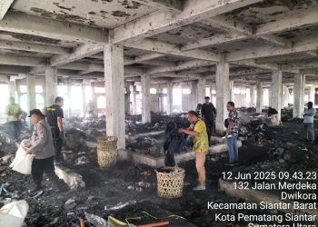 Kasub Sektor Pasar Horas, AIPTU Edi Syahputra SH, melakukan pembersihan sisa barang dagangan yang terbakar di Gedung 4 Lantai 2 Pasar Horas, Jalan Merdeka Pematangsiantar, pada Kamis (12/6/2025) pagi.