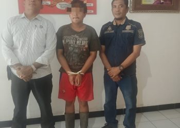 Foto pelaku diapit petugas.