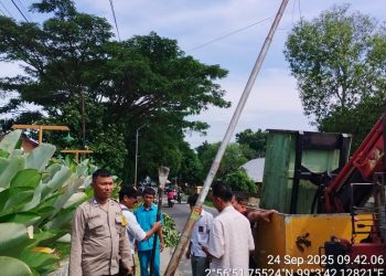 Bhabinkamtibmas Kelurahan Kristen, BRIPKA Swandi, mendampingi instansi terkait dalam perbaikan tiang listrik akibat angin puting beliung, di Jalan Bahagia Pematangsiantar, pada Rabu (24/9/2025) siang.