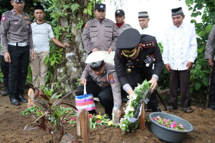 Kapolres AKBP Ronald F C Sipayung SH SIK MH menaburkan bunga ke pusara Aiptu Arie Kismono
Foto: IST