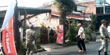 Satpol PP menertibkan spanduk di jalan Medan