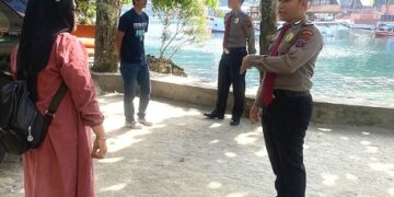 Personel berbincang dengan pengunjung di lokasi wisata