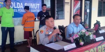 Kapolres memberi keterangan pers dan pelaku mengenakan seragam oranye berdiri di bagian belakang.