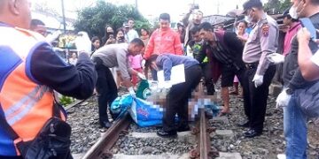 Petugas mengevakuasi jenazah dari rel kereta api