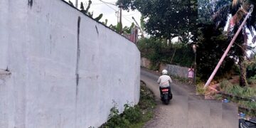 Tembok yang dipermasalahkan dan tiang listrik yang miring