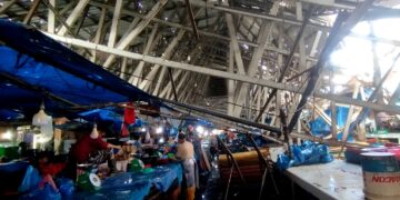 Pedagang berjualan di bawah atap yang rubuh