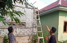 Personel Polsek Raya Kahean dan warga mengamati rumah yang rusak