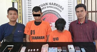 Kedua tersangka dan barang bukti diapit petugas