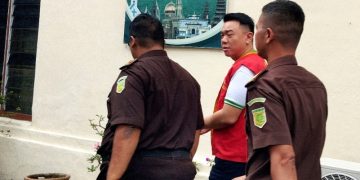 Terdakwa  diapit petugas Kejaksaan