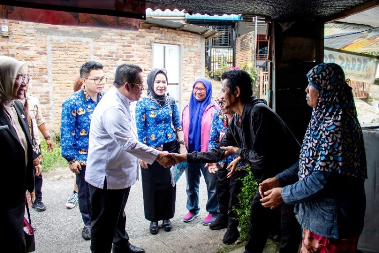 Walikota bersalaman dengan penghuni yang menempati rumah tidak layak huni