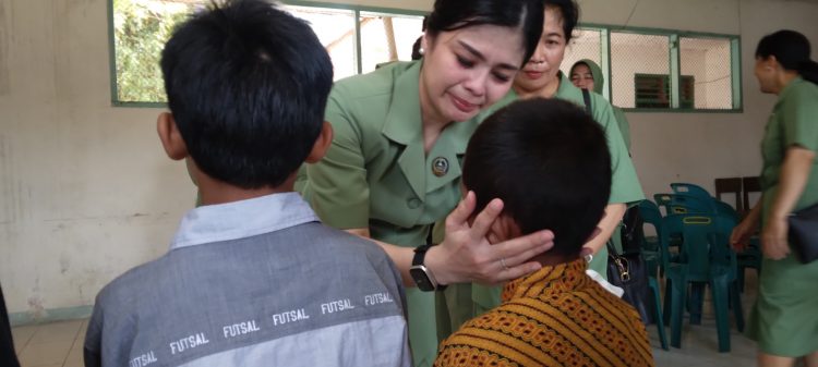 Ketua KCK Paramita Edward meneteskan air mata sembari memegang wajah anak panti dengan kasih