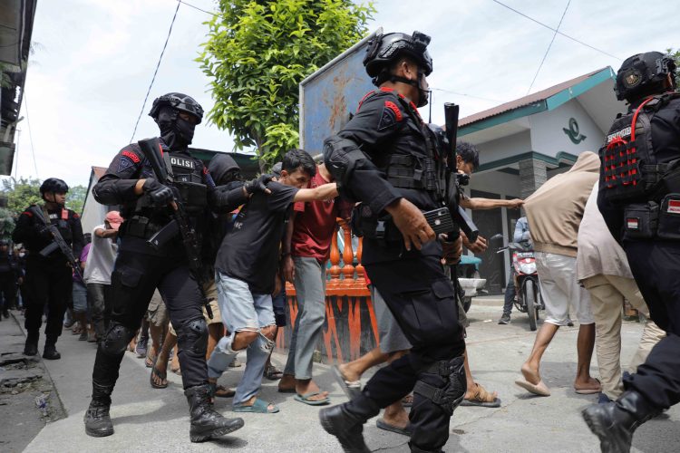 Personel Brimob Polda Sumut mengamankan BNNP Sumut dan Polrestabes Medan serta tahanan kasus narkotika saat konferensi pers pengungkapan kasus narkoba di pinggiran Sungai Lingkungan Pria Laut III, Jalan Balai Desa, Kelurahan Lalang, Kecamatan Medan Sunggal, Jumat (7/11/2025).DHEV BAKKARA