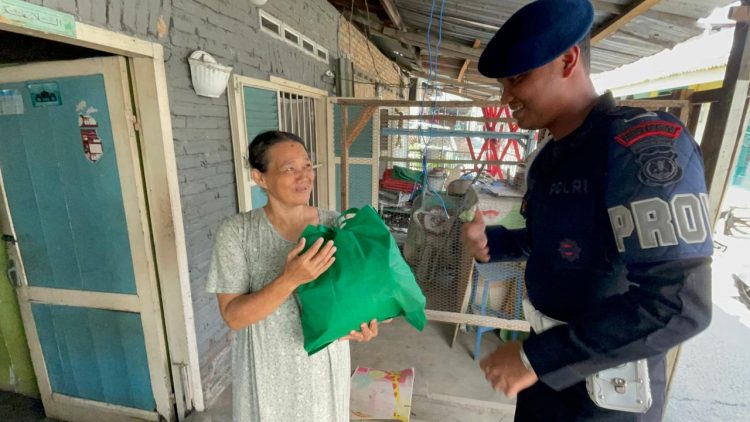 Personel Brimob Batalyon A Pelopor Satuan Brimob Polda Sumut membagikan paket sembako kepada warga dalam kegiatan “Berbagi Kasih di Hari Minggu”