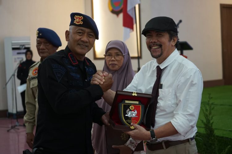 Dansat Brimob Polda Sumut, Kombes Pol Rantau Isnur Eka, S.I.K., M.M., M.H., M.Han., menyerahkan plakat penghargaan kepada narasumber dalam kegiatan Sarasehan Brimob Presisi HUT ke-80 Korps Brimob Polri di Medan.