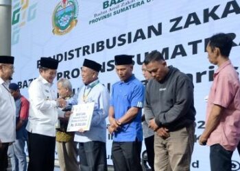 Pj Gubernur Sumut Hassanudin menyerahkan zakat ASN Pemprov Sumut kepada pengurus BAZNAS.